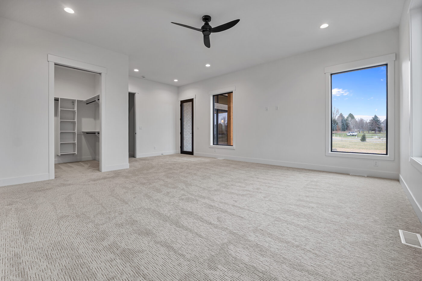 Main floor primary bedroom with ceiling fan and large windows at 560 Partridge Lane